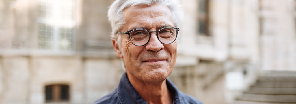An older male wearing glasses, smiling at the camera 